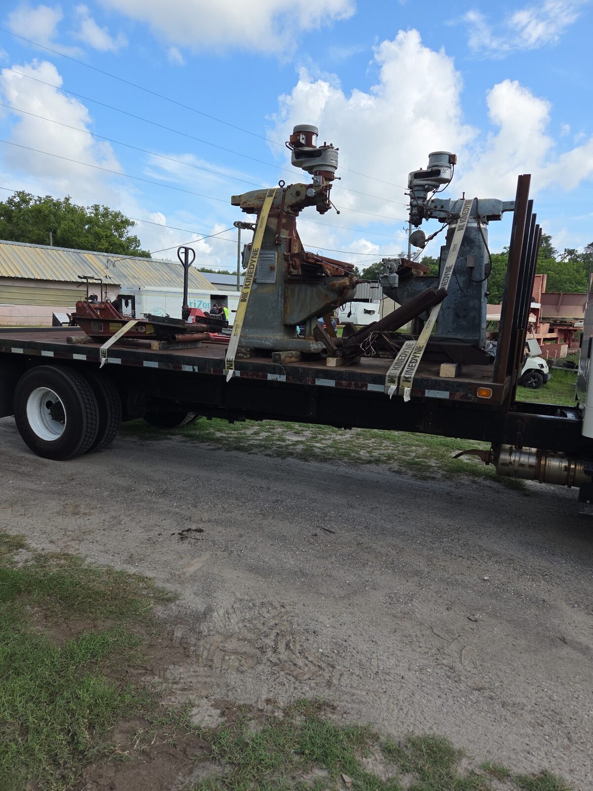 Industrial machinery being placed by a Moffett piggyback forklift off a flatbed