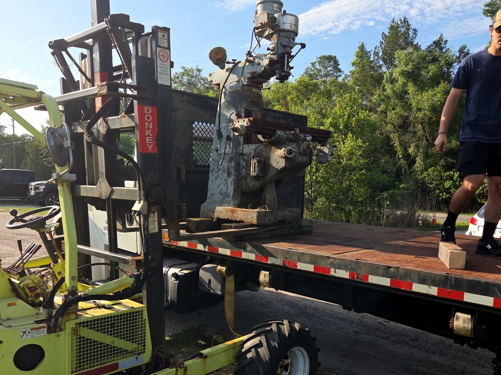 Industrial milling machine secured on a flatbed truck with an on-board forklift for offload
