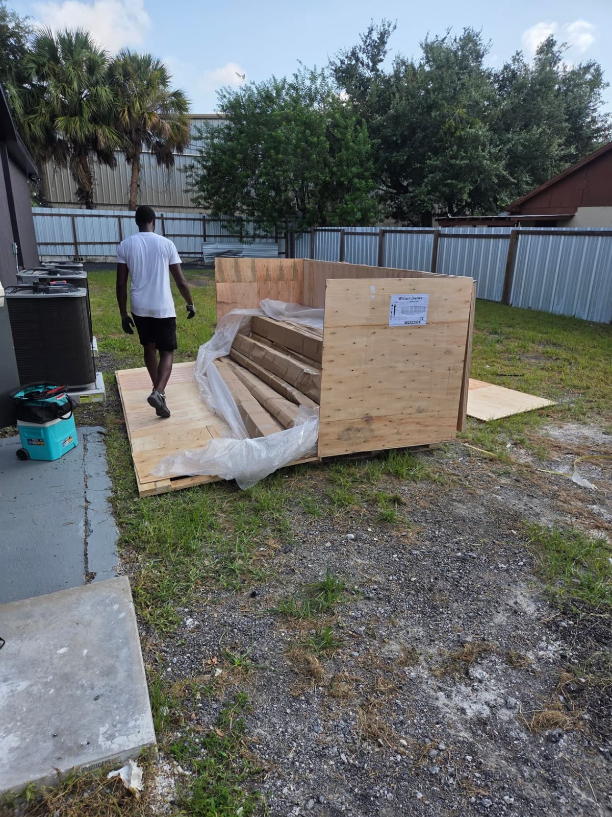JIT crew member carefully opening a large shipping crate after it was placed at the destination
