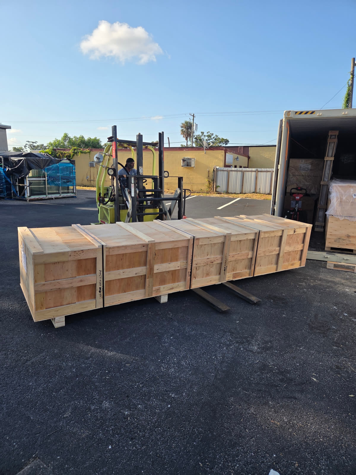 JIT operator positioning a long wooden shipping crate after unloading it from a grounded container